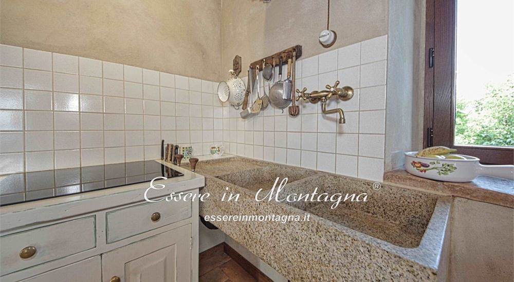 La sala con camino, tavolone, stube e cucina